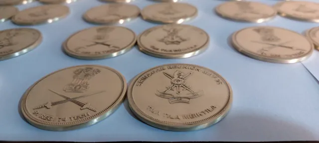 Close-up of polished brass Indian Army coins with unit crests