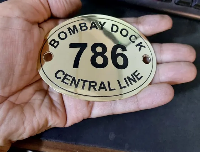 Oval brass railway-style plate with black lettering