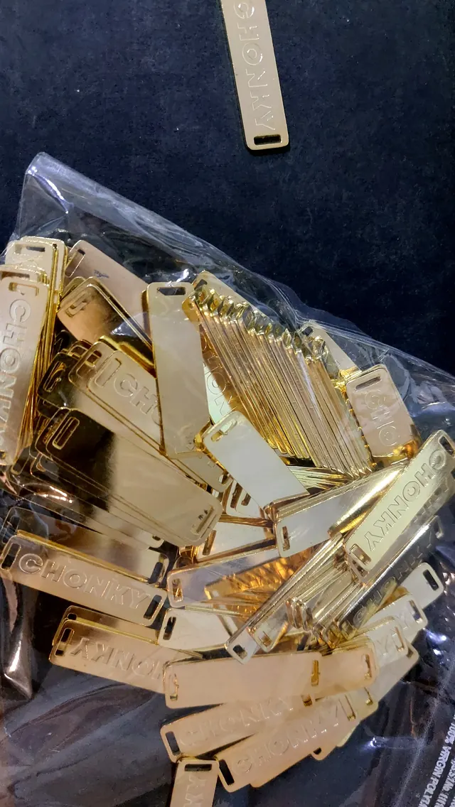 A bag of polished brass labels ready for dispatch